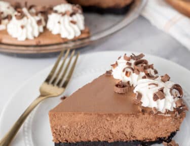 Slice of Chocolate Satin Pie on a plate with extra chocolate curls on the side.