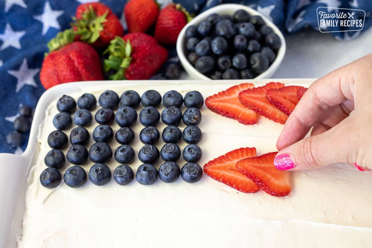 Placing a sliced strawberry on top of 4th of July Cake.