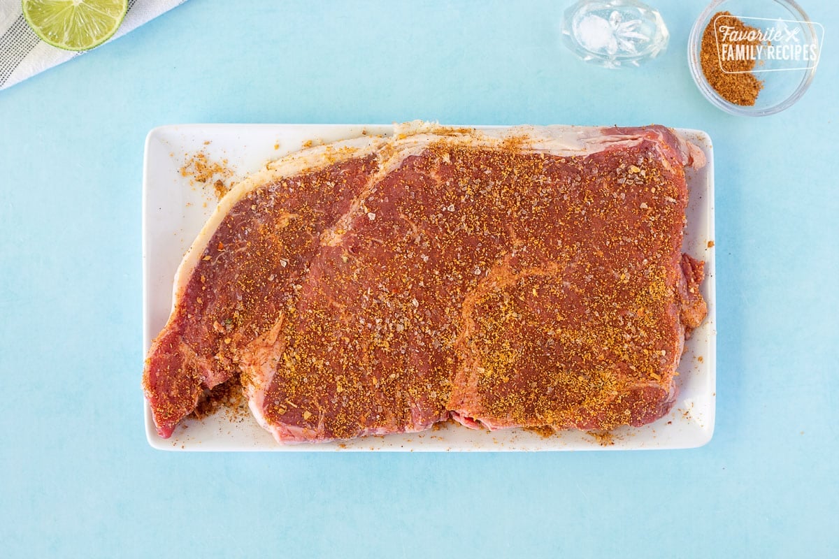 Seasoning steak on a plate for Street Tacos.