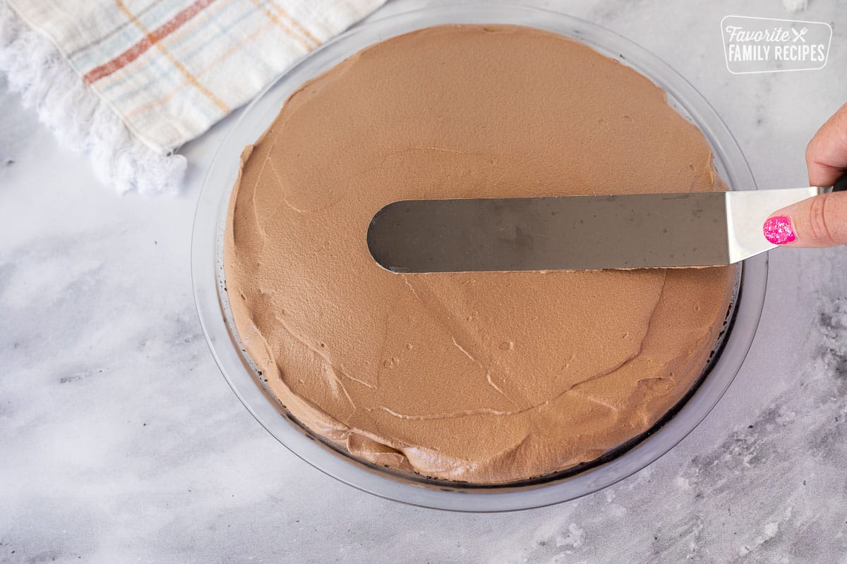 Smoothing top of Chocolate Satin Pie with a flat spatula.
