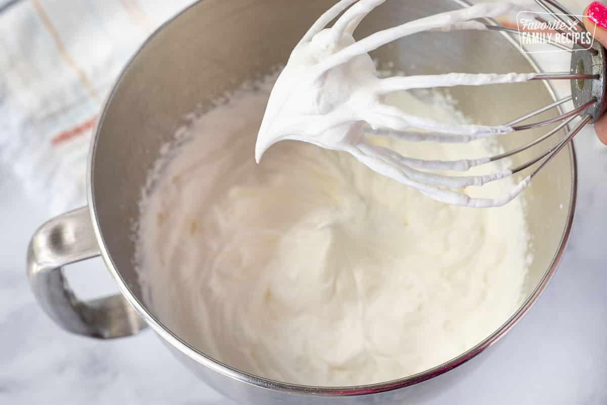 Mixing bowl of whipped cream with mixer whisk for Chocolate Satin Pie.