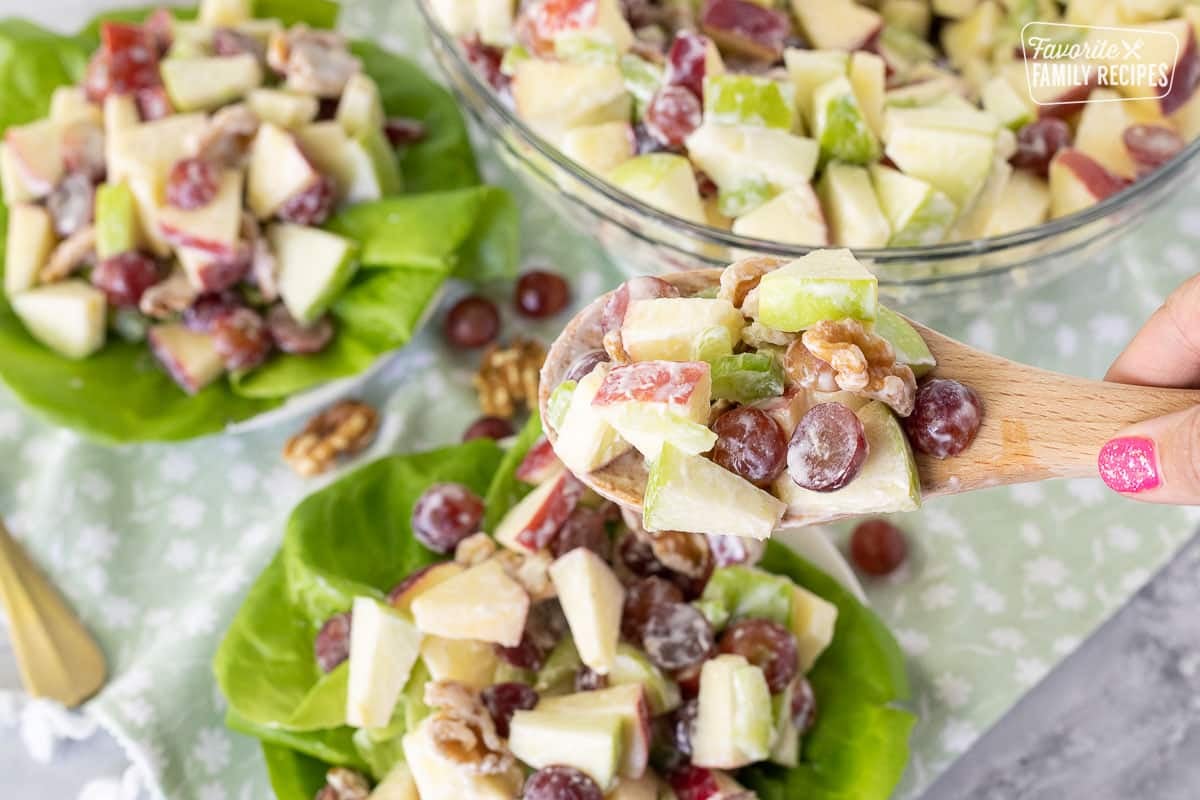 Hand holding a wooden spoon with Waldorf Salad.