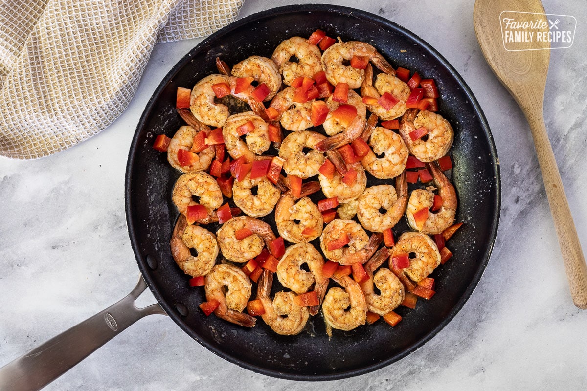 Skillet with shrimp, red peppers and garlic for Creamy Cajun Shrimp Pasta.