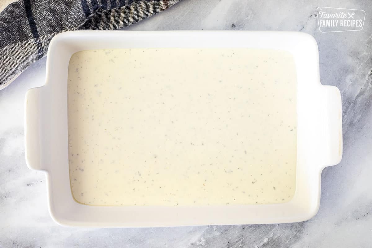 Baking dish with bottom layer of white sauce for White Chicken Lasagna.