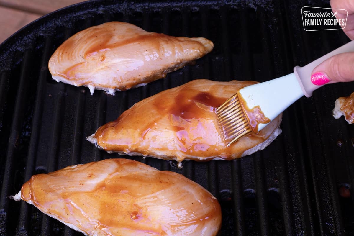 Chicken breasts on the grill with brush basting Honey BBQ sauce on Chicken.