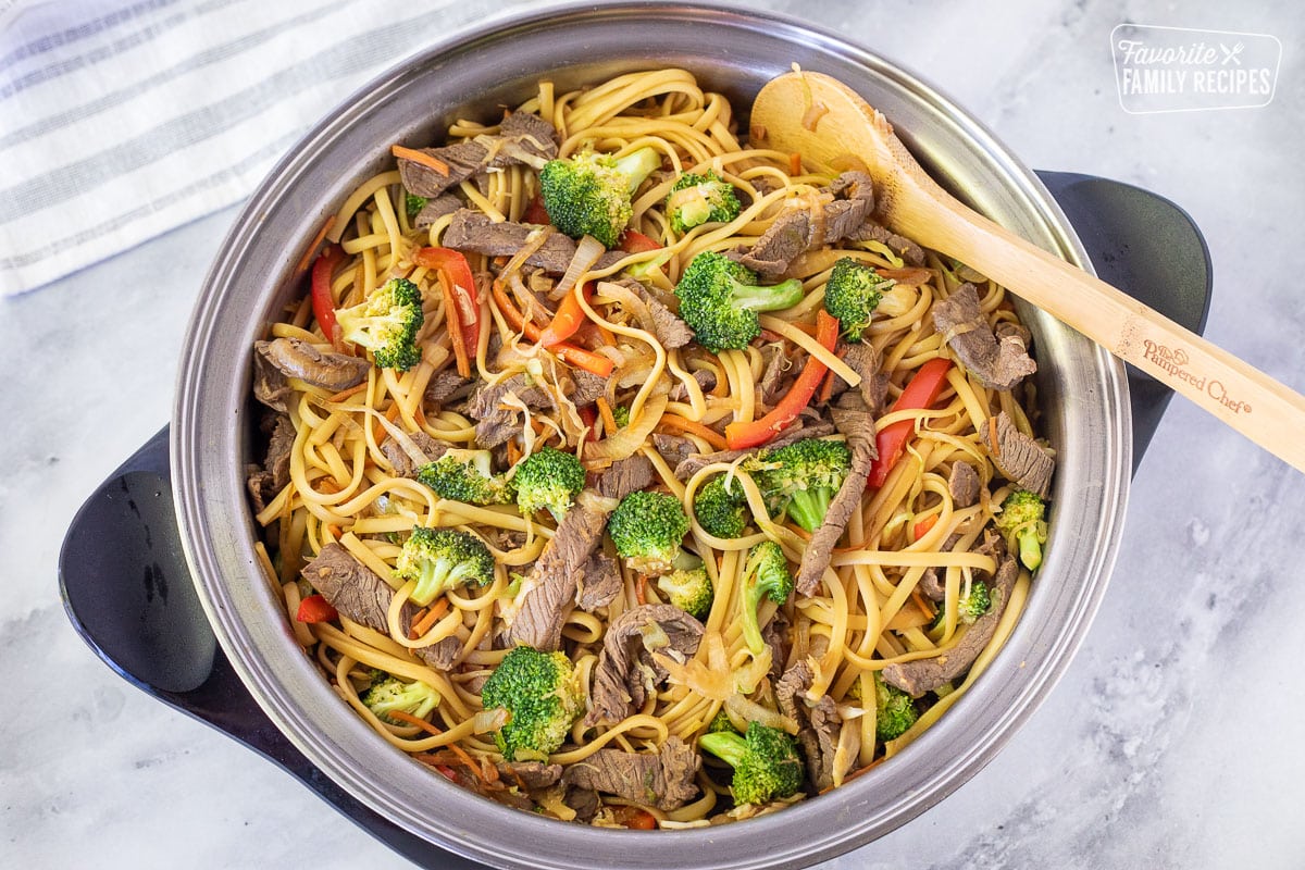 Skillet with Beef Stir Fry with vegetables and noodles with wooden spoon.