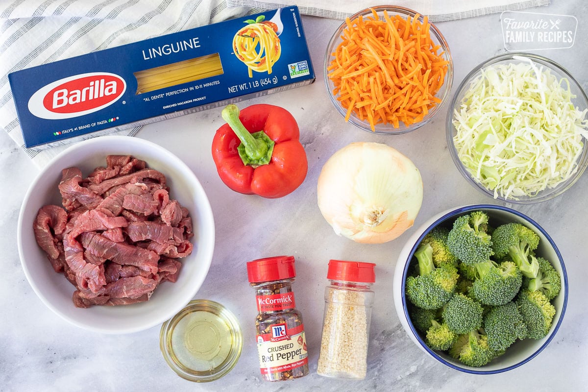 Ingredients for Beef Stir Fry including linguine, carrots, cabbage, red peppers, onion, beef, oil, broccoli, red pepper and sesame seeds.