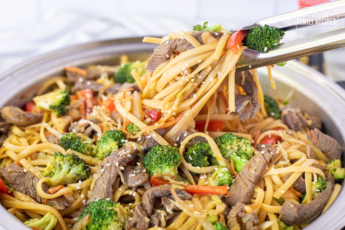 Lifting Beef Stir Fry from skillet with tongs.