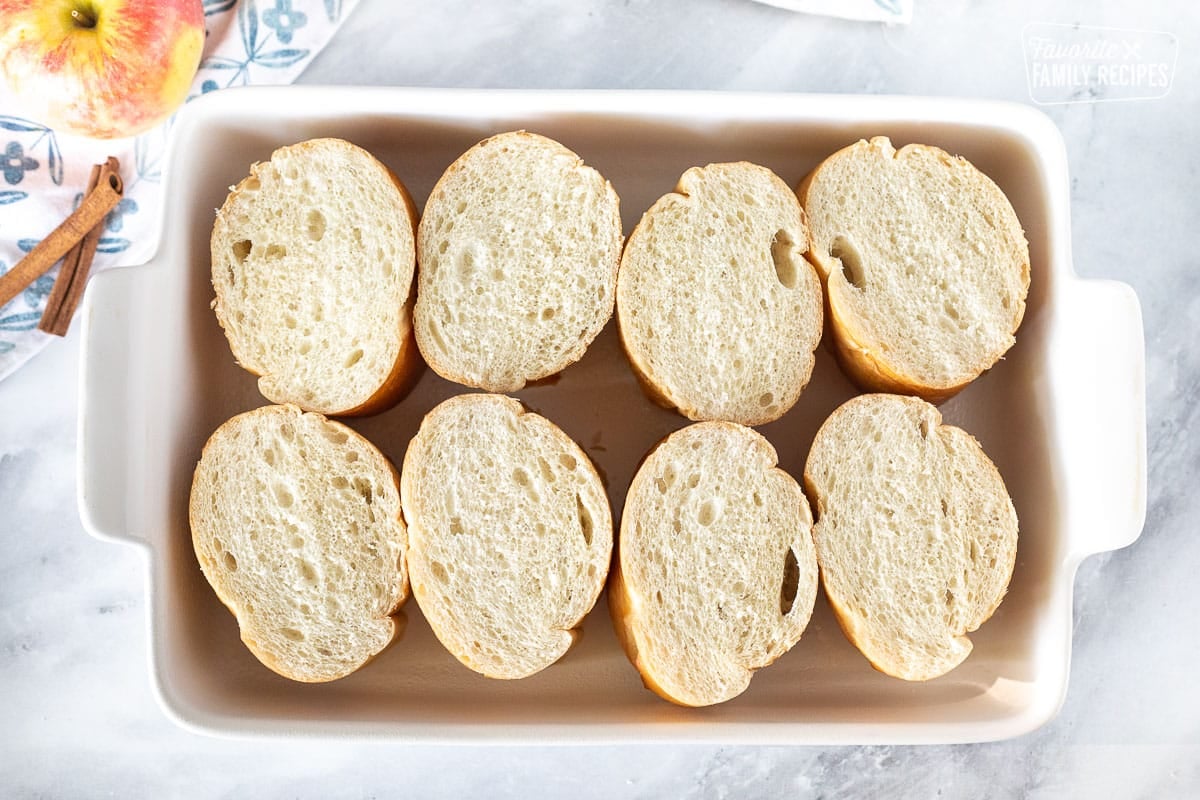 Sliced French bread arranged in a baking dish for Caramel Apple French Toast Casserole.