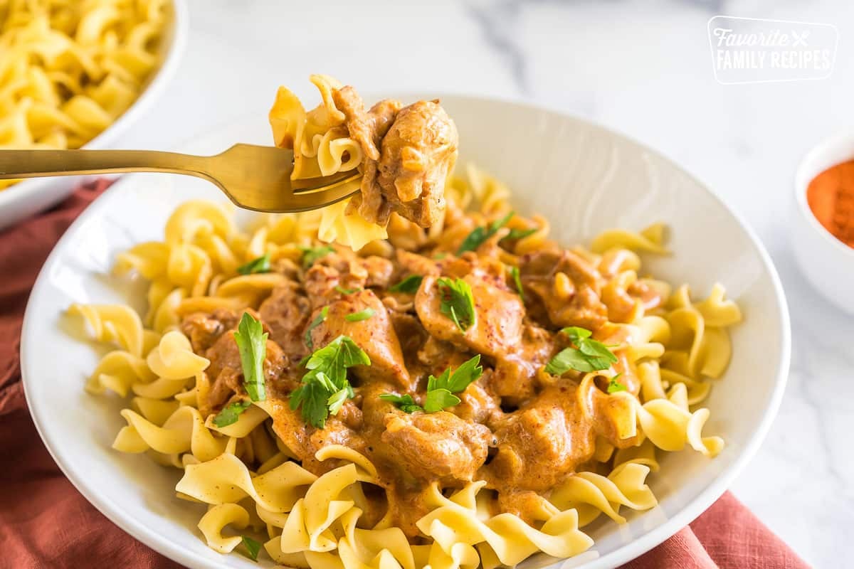 Chicken Paprikash in a bowl topped with parsley with a fork taking a bit out of it