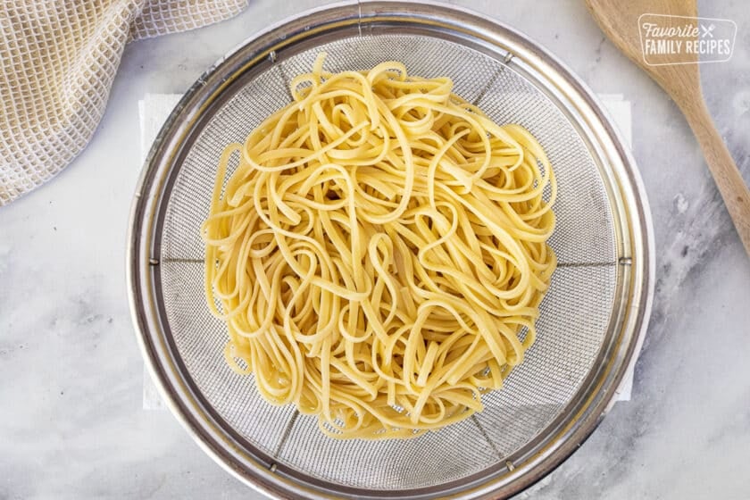 Colander with cooked linguine for Creamy Cajun Shrimp Pasta.