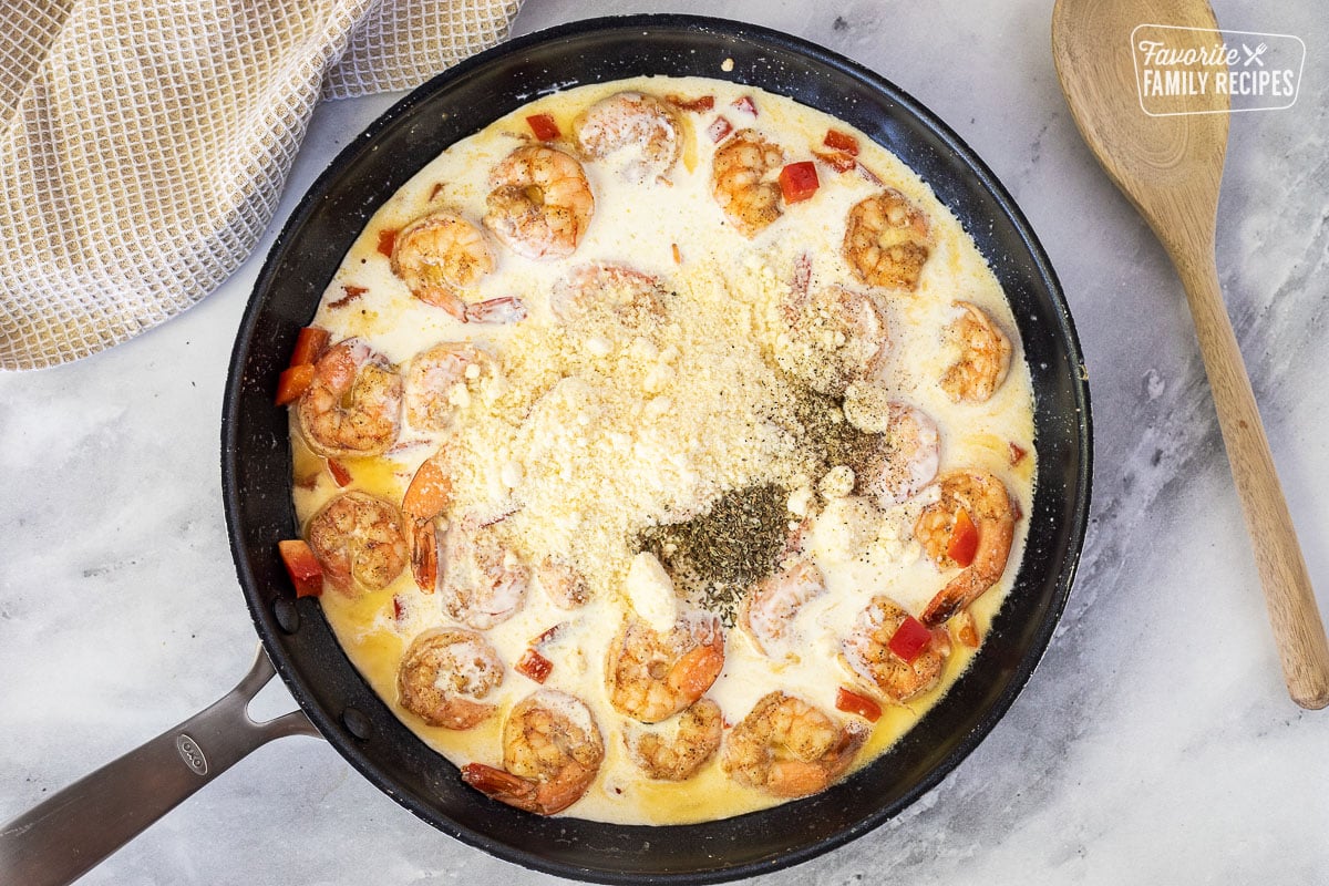 Skillet with cream, cheese and basil added for Creamy Cajun Shrimp Pasta.