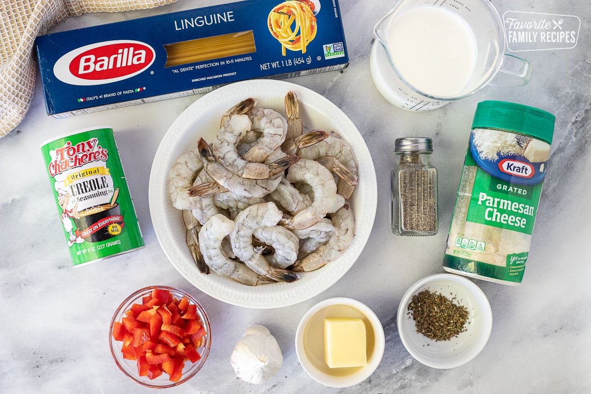 Ingredients to make Creamy Cajun Shrimp Pasta including shrimp, creole seasoning, linguine, cream, parmesan cheese, pepper, basil, butter, garlic and red peppers.