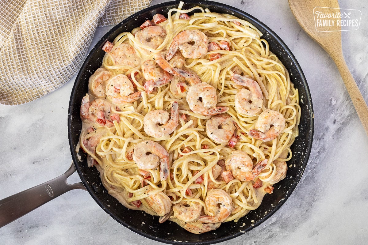 Skillet with pasta and shrimp combined for Creamy Cajun Shrimp Pasta.