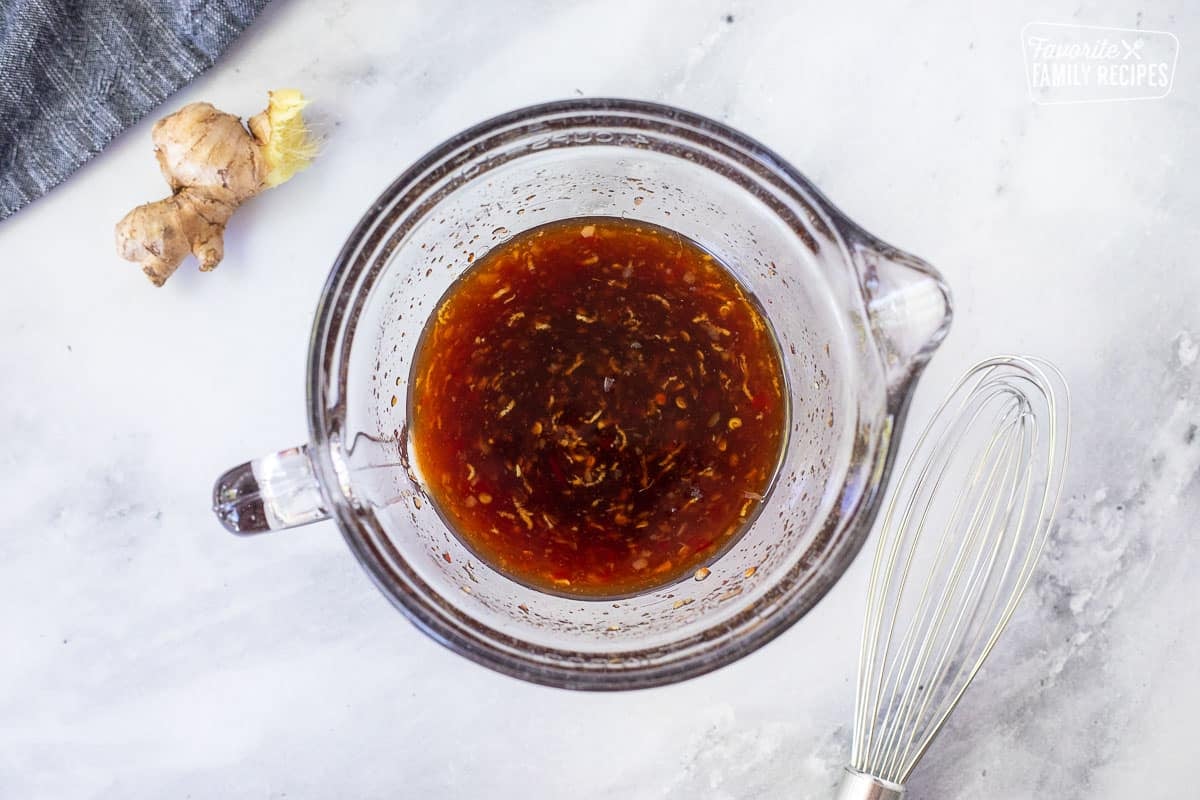 Mixing bowl with crock pot ribs sauce next to whisk.