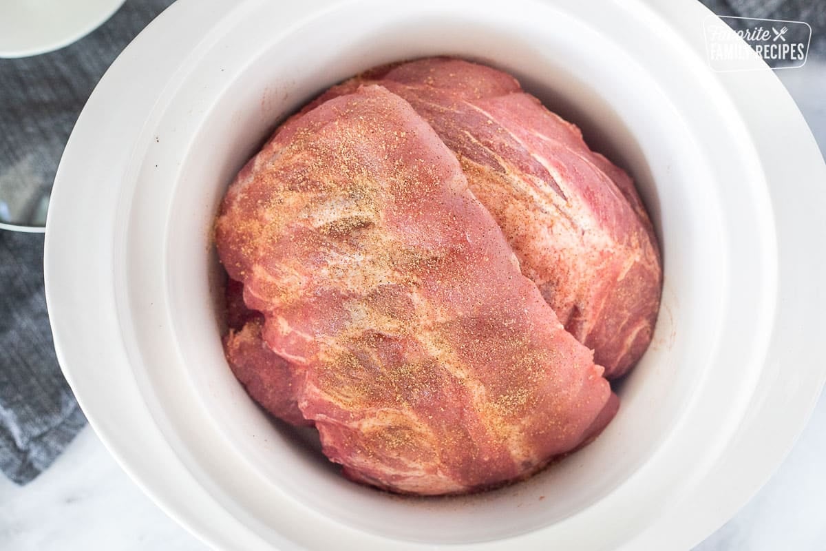 Crockpot with uncooked racks of ribs seasoned with seasoning salt.