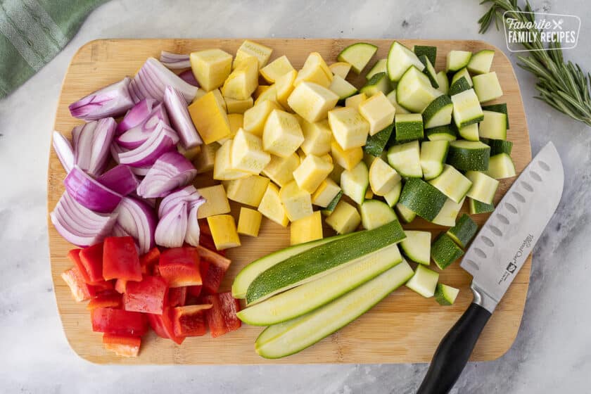 Cutting board with sliced vegetables and a knife for Oven Roasted Vegetables.