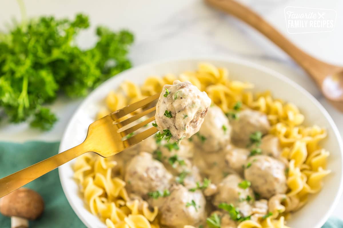 A bowl of easy meatball stroganoff with one meatball on a fork