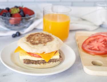 Freezer Breakfast Sandwich with sliced tomato on a plate.