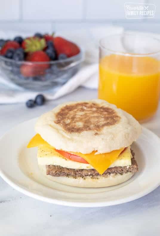 Freezer Breakfast Sandwich on a plate. Fresh berries and orange juice on the side.