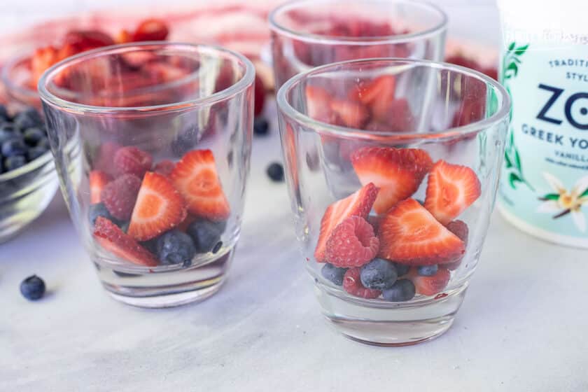 Three glasses with fruit on the bottom for Breakfast Parfaits.