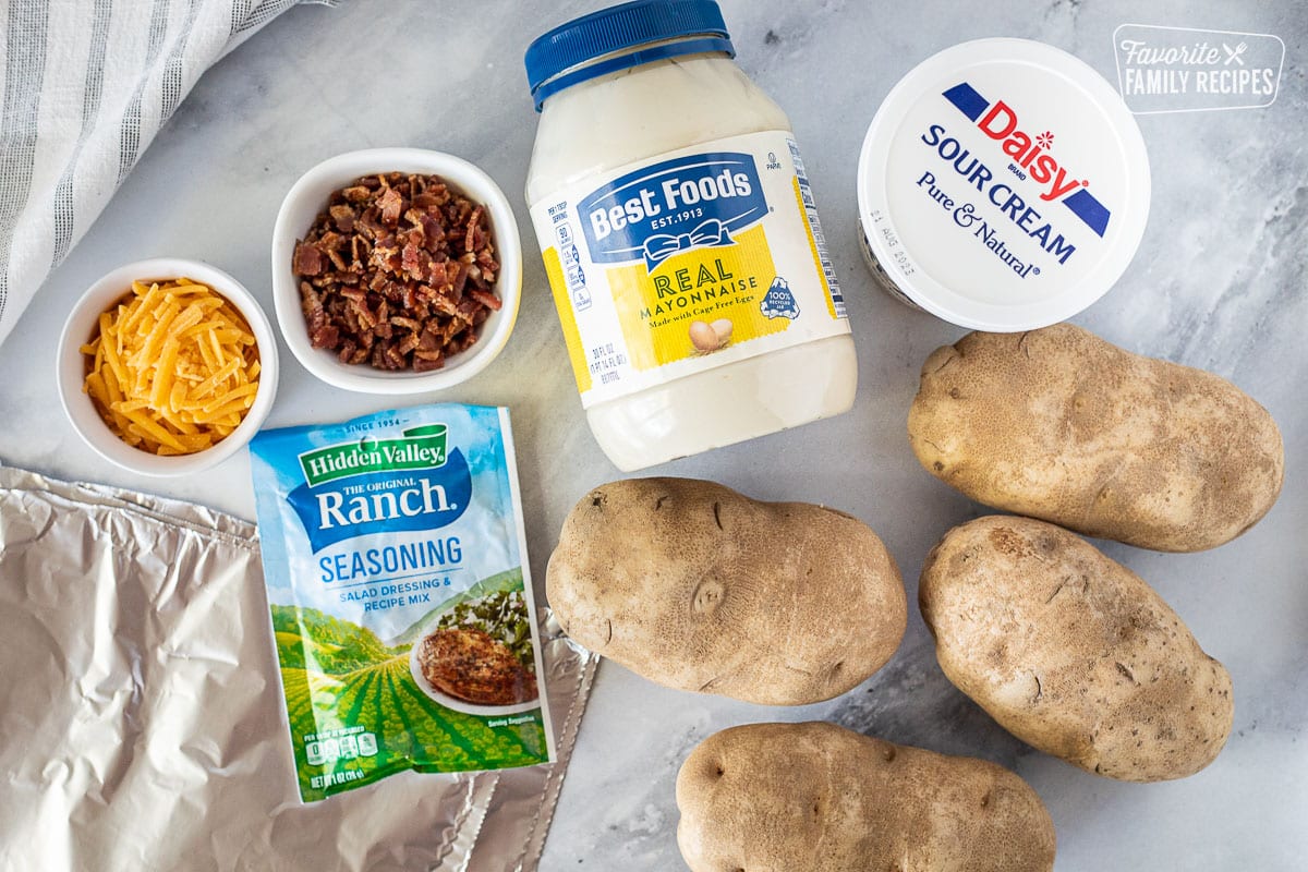 Ingredients to make Grilled Ranch Potatoes in Foil including mayo, sour cream, potatoes, bacon, cheese, ranch seasoning packet and foil.
