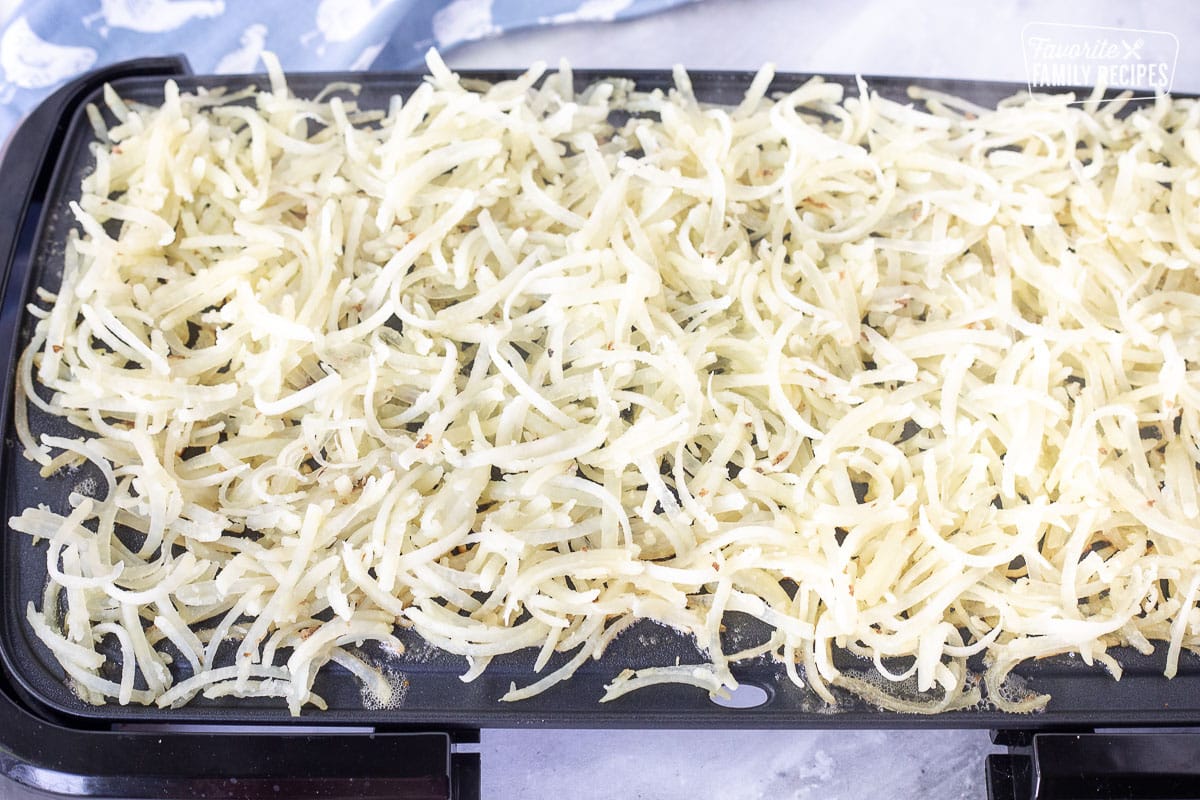 Showing how to make Hash Browns on a griddle with butter.
