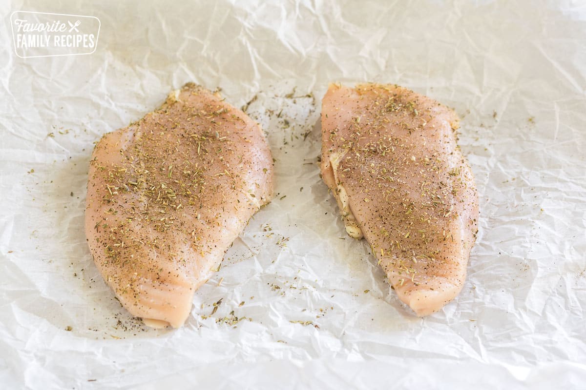 two raw pieces of chicken with seasonings