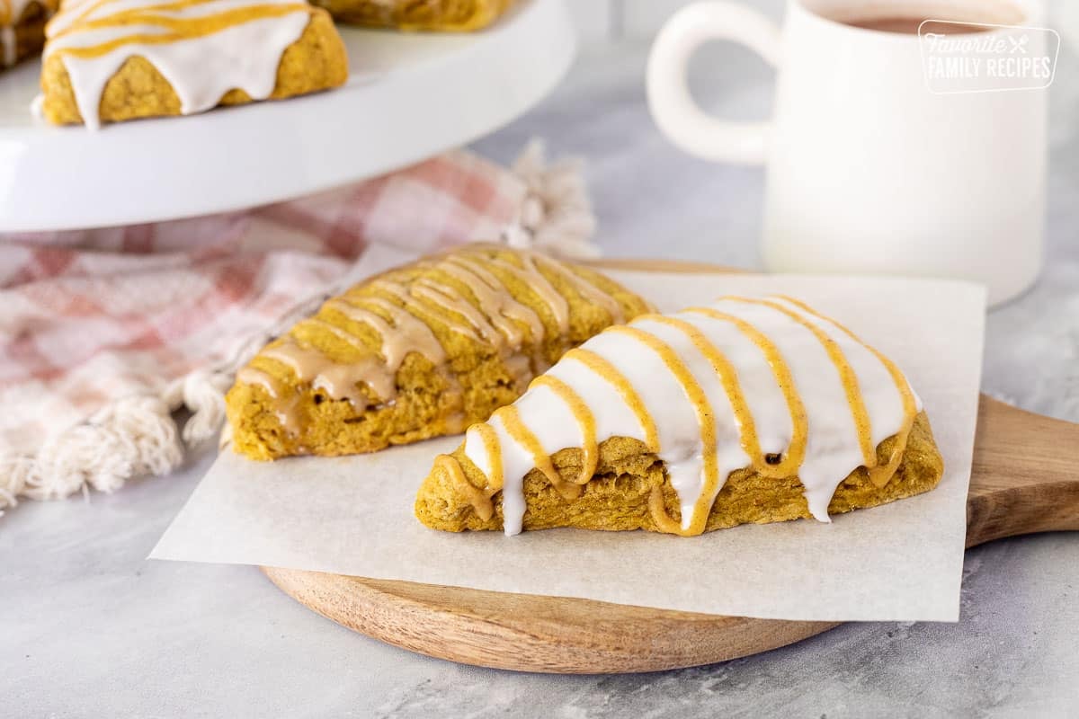 Pumpkin scones with maple glaze and Starbucks white and pumpkin glaze on parchment paper.
