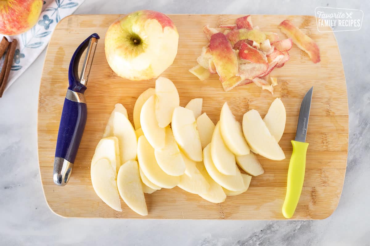 Cutting board with peeled and sliced apples for Caramel Apple French Toast Casserole.