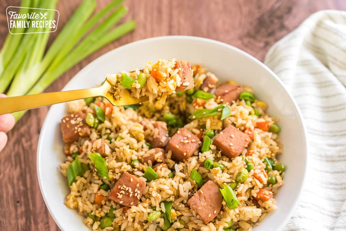 Spam fried rice in a bowl with a bite being taken out on a fork