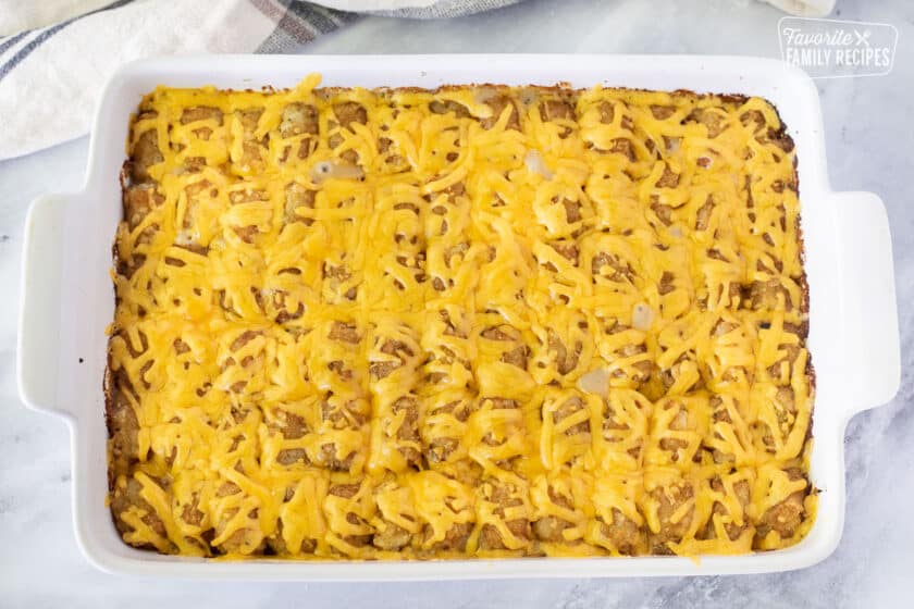 Baking dish with Tater Tot Casserole topped with melted cheddar cheese.