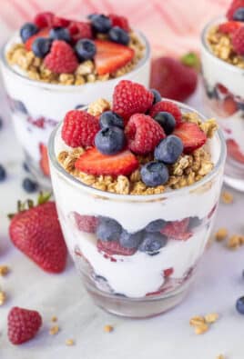 Three assembled Breakfast Parfaits with yogurt, fresh berries and granola.
