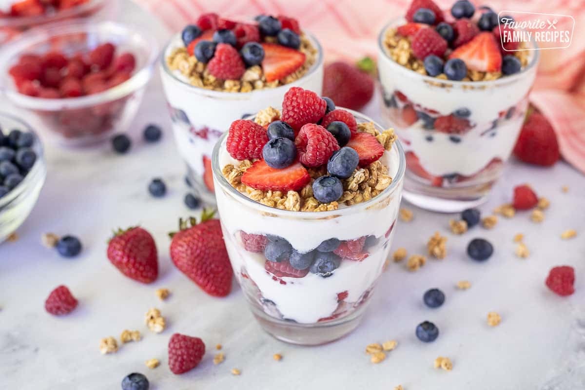 Three assembled Breakfast Parfaits with yogurt, fresh berries and granola.