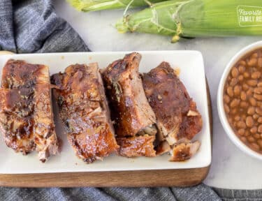 Cut up sections of Crock Pot Ribs on a plate. Beans and corn on the side.