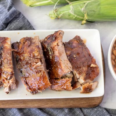 Cut up sections of Crock Pot Ribs on a plate. Beans and corn on the side.