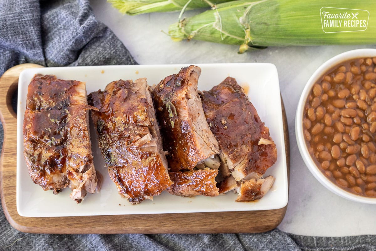 Cut up sections of Crock Pot Ribs on a plate. Beans and corn on the side.