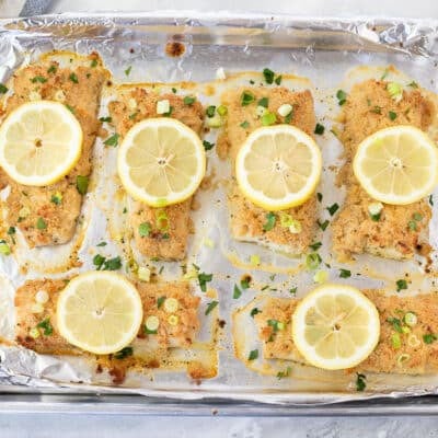 Baked Mahi Mahi with Parmesan Crust. Sliced lemons and green onion on top.