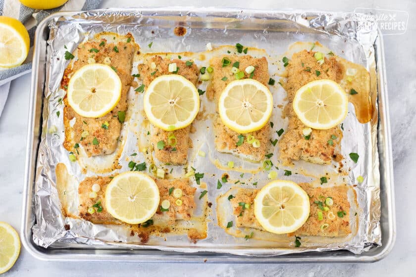 Baked Mahi Mahi with Parmesan Crust. Sliced lemons and green onion on top.