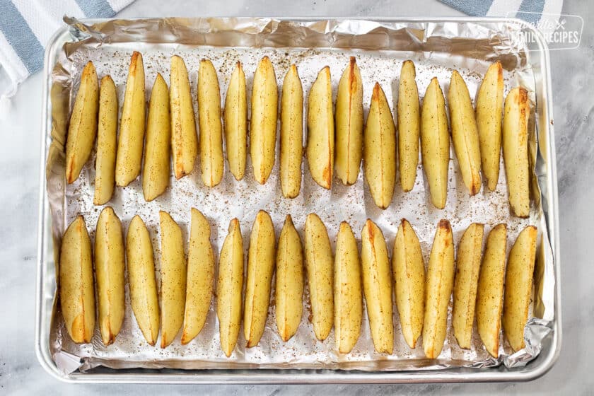 Cookie sheet lined with foil and baked potato wedges.