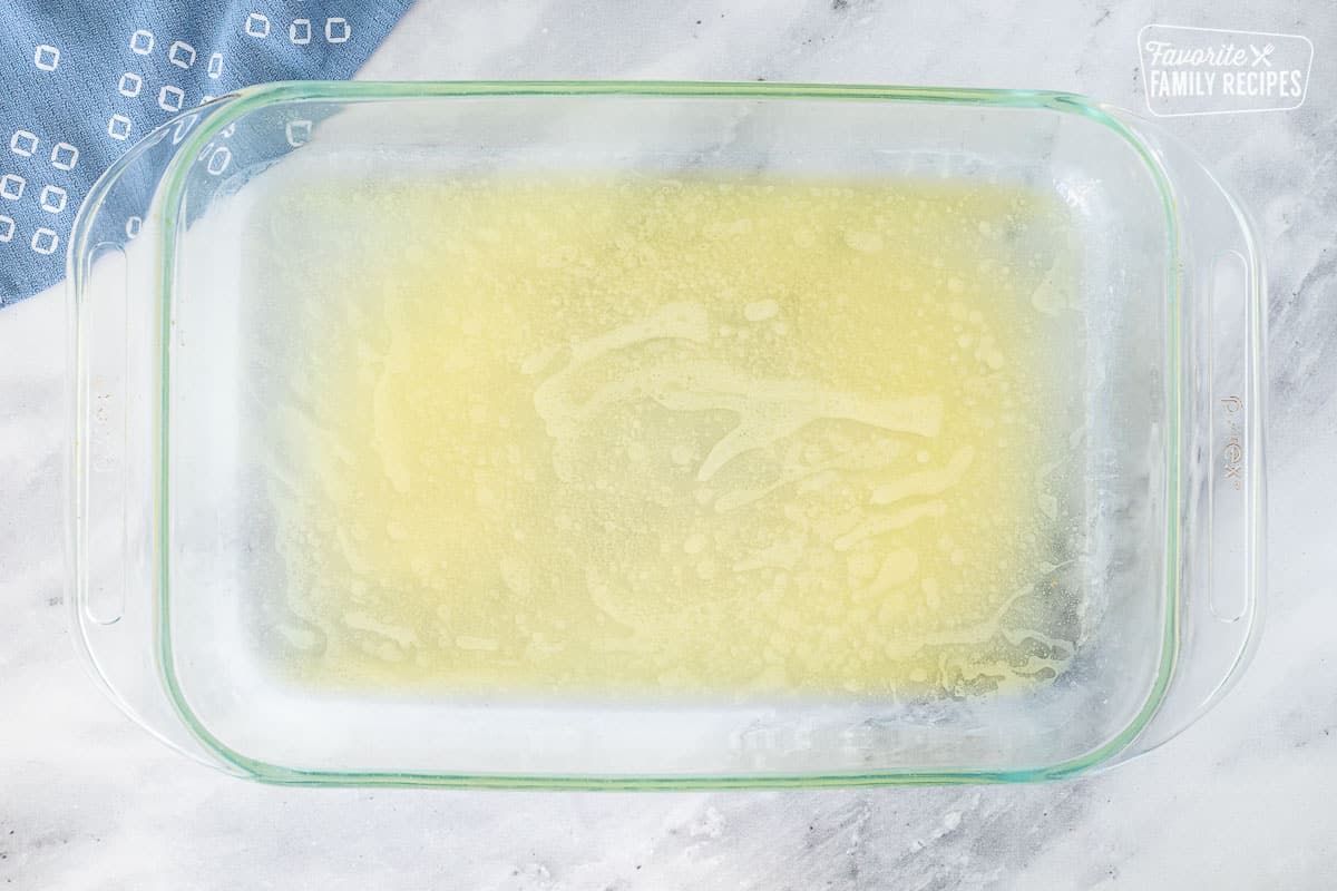 Baking dish with melted butter for Parmesan Crusted Potatoes.