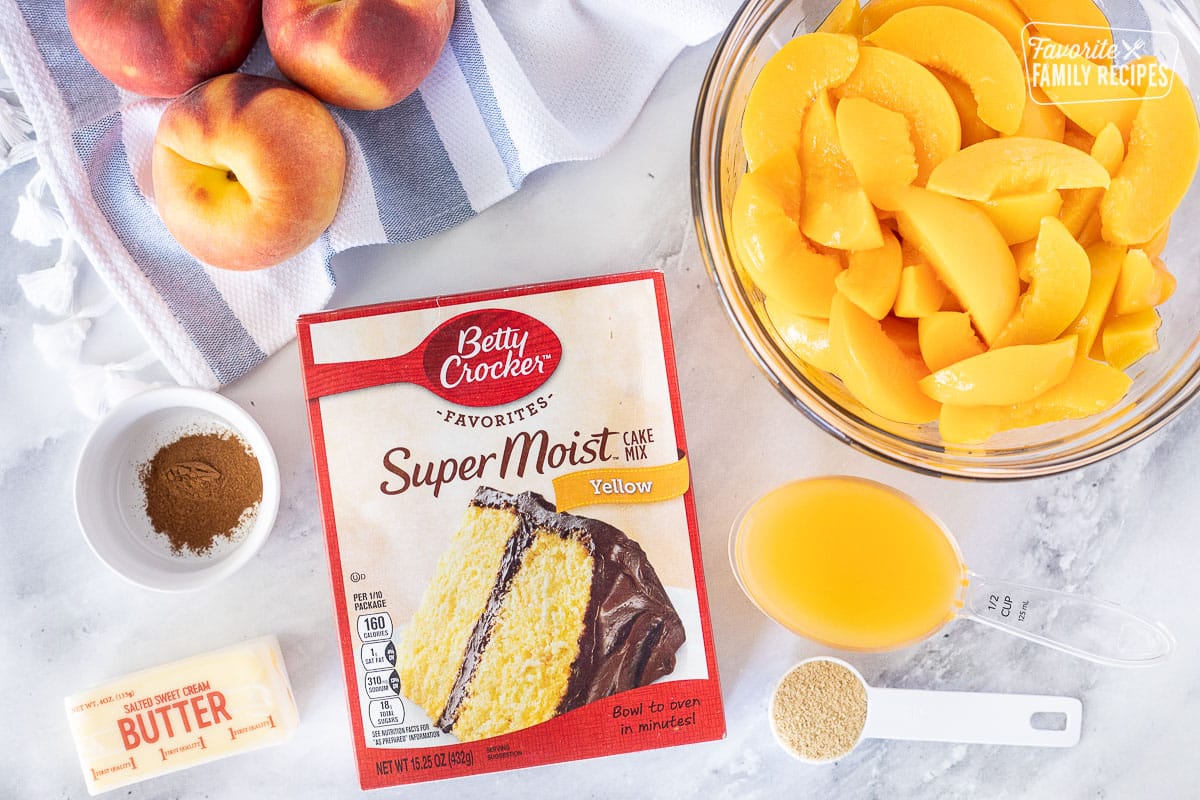 Ingredients to make Crock Pot Peach Cobbler including peaches, cake mix, cinnamon, butter, peach juice and brown sugar.