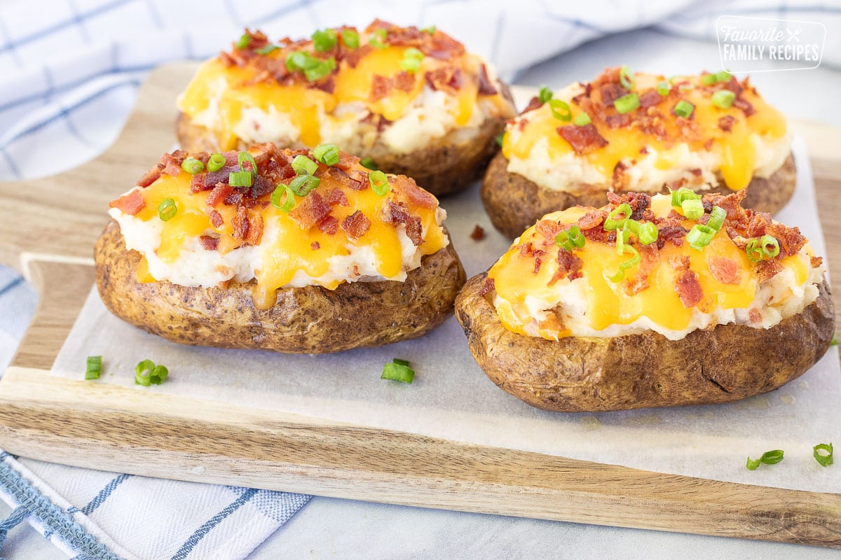 Four Twice Baked Potatoes on a cutting board.