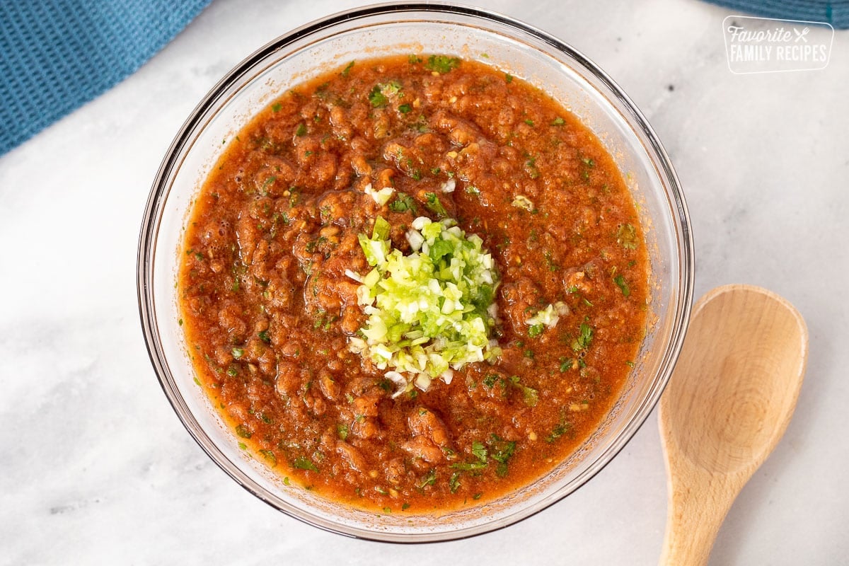 Mixing bowl of blended Salsa with chopped green onion on top.