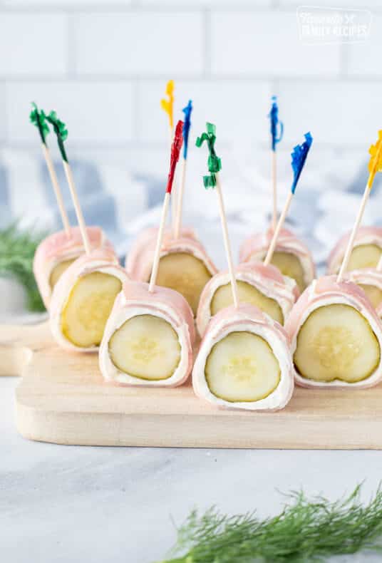 Ham Roll Up with Pickle stabbed with toothpicks on a cutting board.