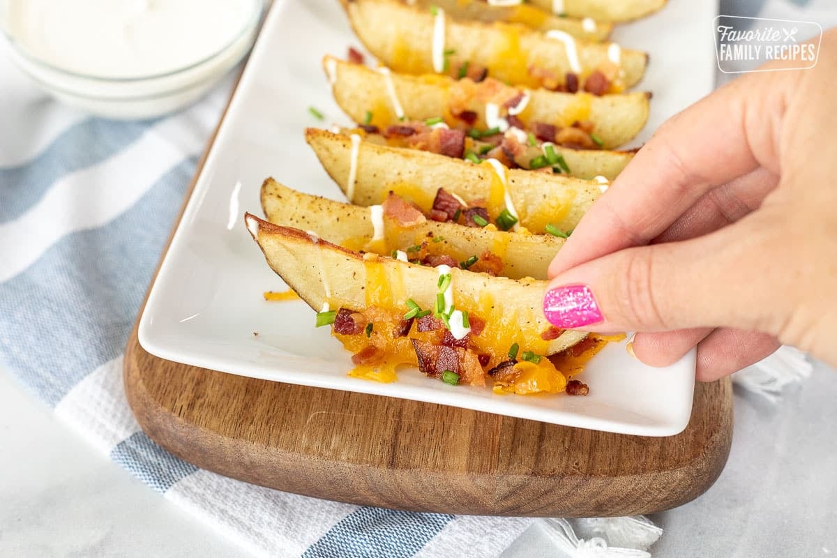 Hand picking up a Loaded Potato Wedge from a platter.