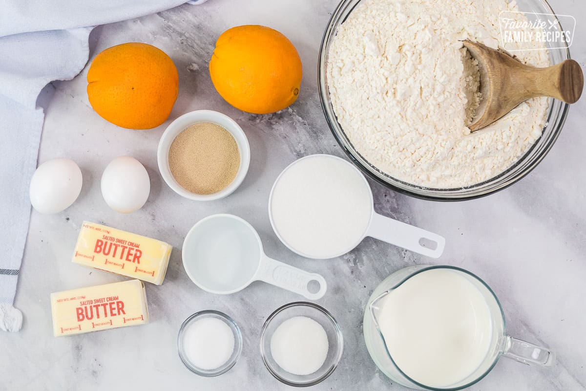 Ingredients to make Homemade Orange Rolls including oranges, flour, milk, water, yeast, eggs, butter, salt and sugar.