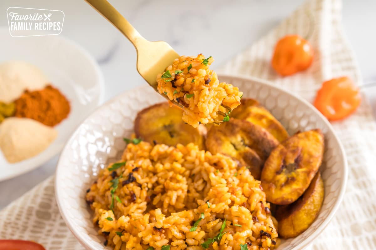 A forkful of jollof rice being taken out of a bowl