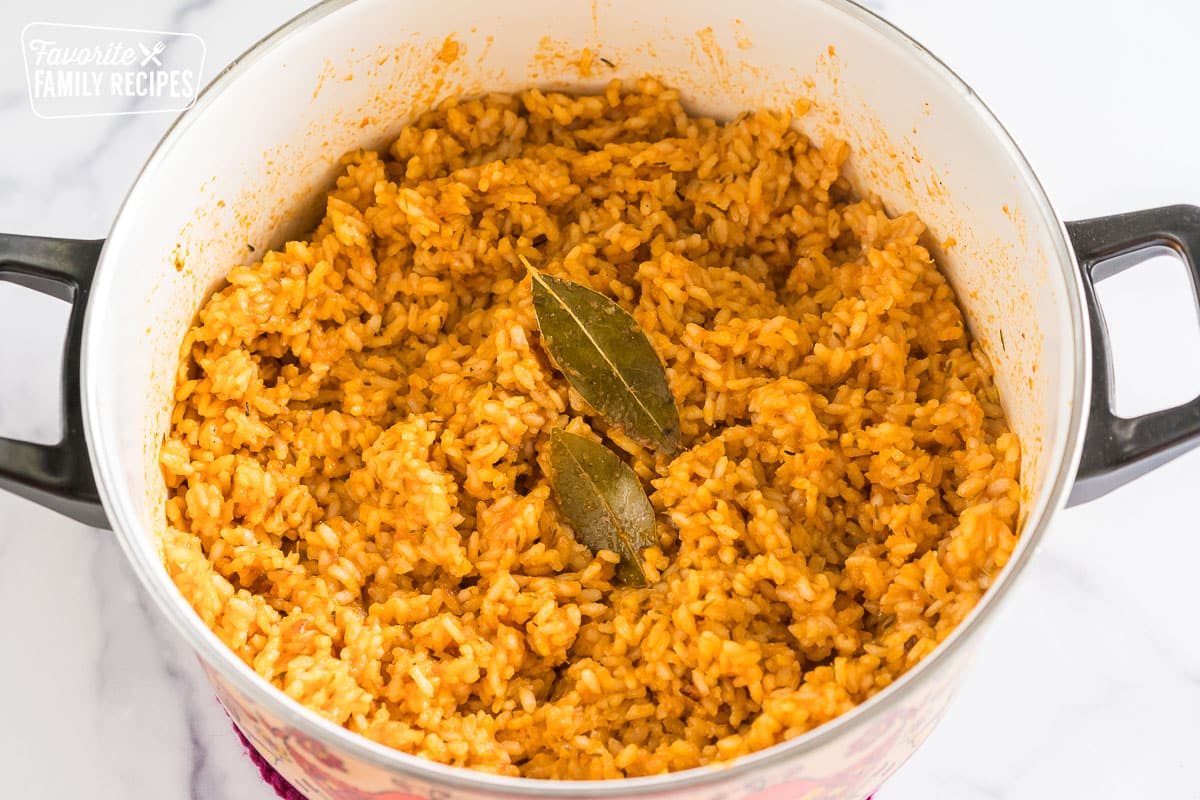 jollof rice in a pot topped with two bay leaves