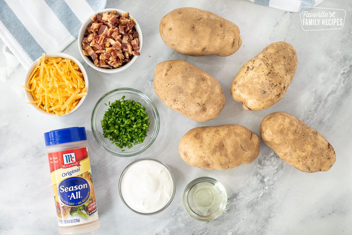 Ingredients to make Loaded Potato Wedges including potatoes, bacon, cheese, chives, seasoning, oil and sour cream.